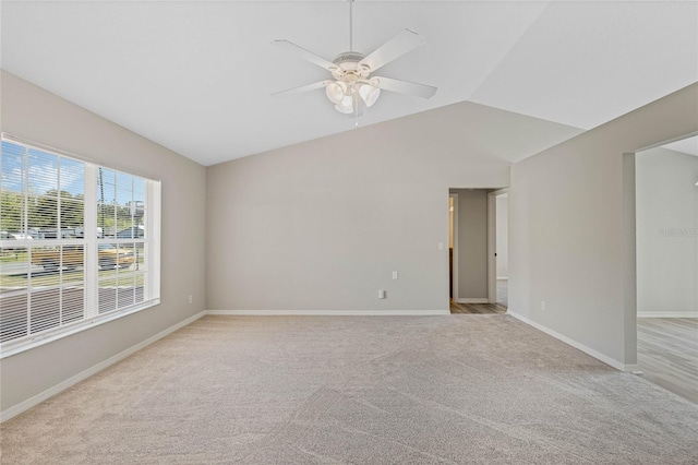 spare room with light colored carpet, baseboards, a ceiling fan, and vaulted ceiling