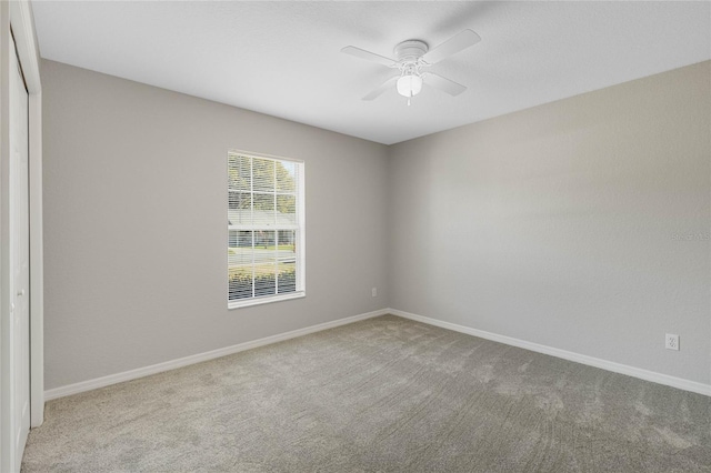 carpeted spare room featuring a ceiling fan and baseboards