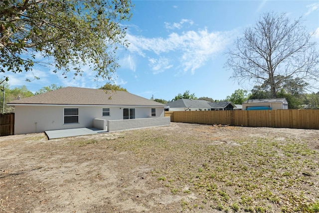 rear view of property with a patio, fence, and stucco siding