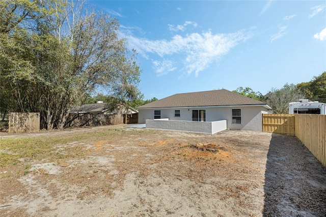 rear view of house featuring a patio area, stucco siding, and a fenced backyard