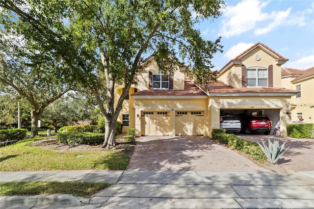 view of front of home with a tile roof, a garage, driveway, and stucco siding