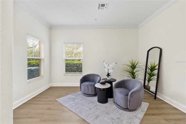 living area with visible vents, baseboards, light wood-style floors, and ornamental molding