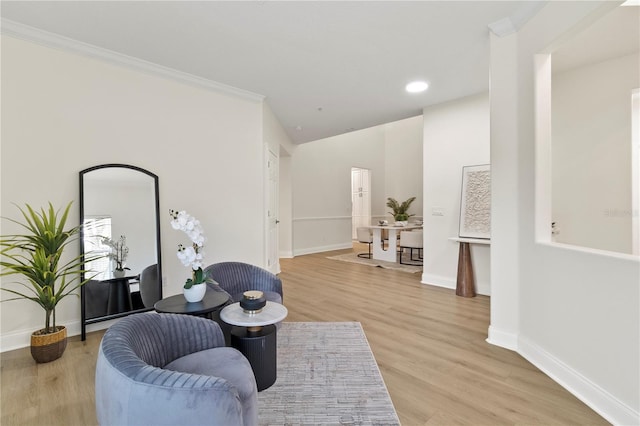 sitting room featuring crown molding, baseboards, and light wood finished floors