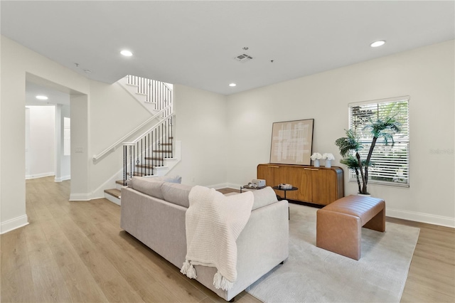 living room featuring visible vents, baseboards, stairway, recessed lighting, and light wood-style floors