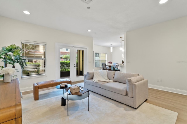 living area with recessed lighting, light wood-type flooring, baseboards, and french doors