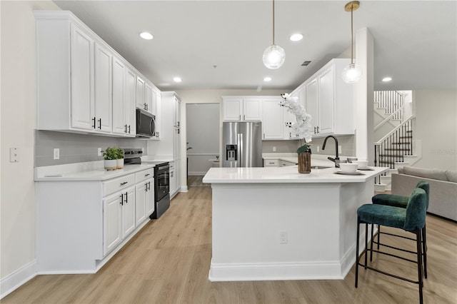 kitchen featuring a sink, stainless steel appliances, light wood-style flooring, and white cabinetry