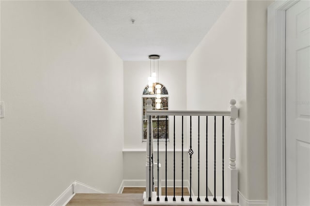 staircase featuring baseboards, a textured ceiling, and wood finished floors