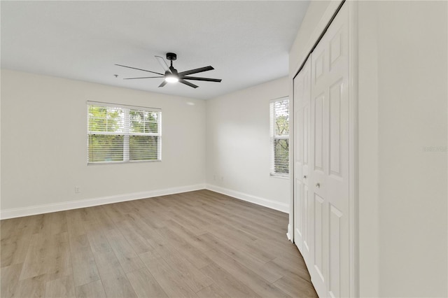 unfurnished bedroom featuring a closet, a ceiling fan, light wood-type flooring, and baseboards