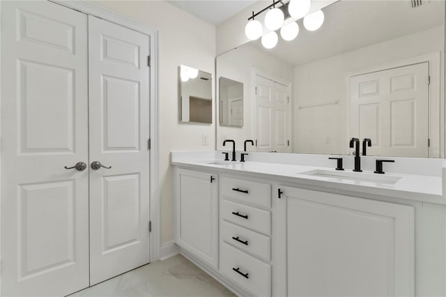 full bathroom with double vanity, marble finish floor, and a sink