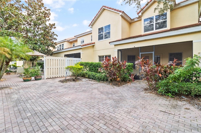 view of front of home with stucco siding, a tile roof, and fence