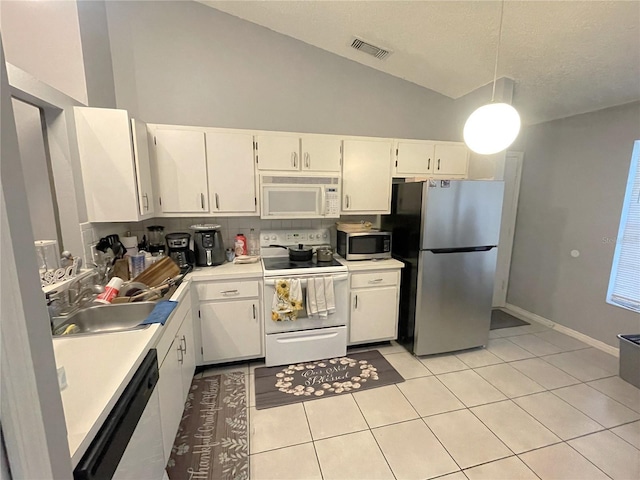 kitchen with light tile patterned floors, vaulted ceiling, appliances with stainless steel finishes, and a sink