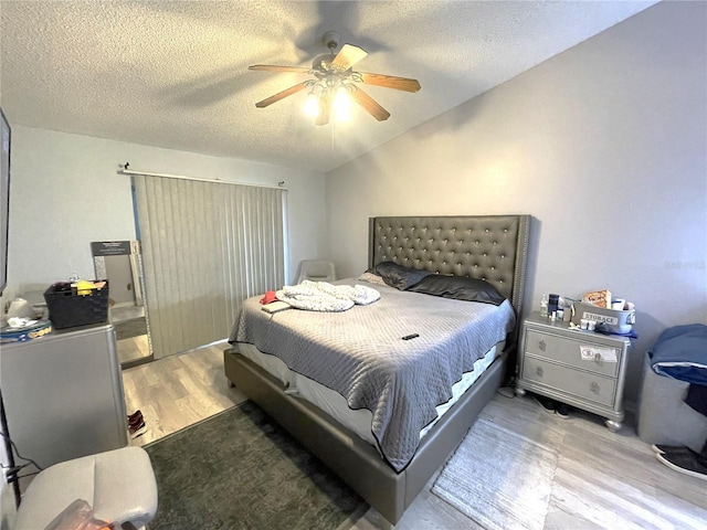 bedroom featuring ceiling fan, a textured ceiling, lofted ceiling, and wood finished floors