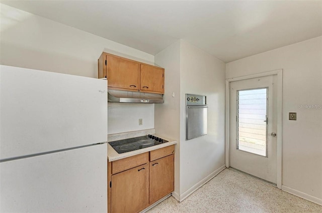 kitchen with oven, under cabinet range hood, freestanding refrigerator, light countertops, and black electric stovetop