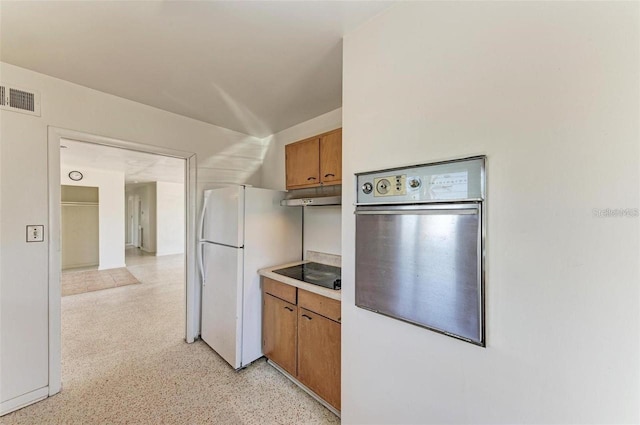 kitchen with visible vents, oven, under cabinet range hood, brown cabinetry, and black electric cooktop