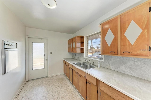 kitchen with baseboards, open shelves, a sink, decorative backsplash, and light countertops