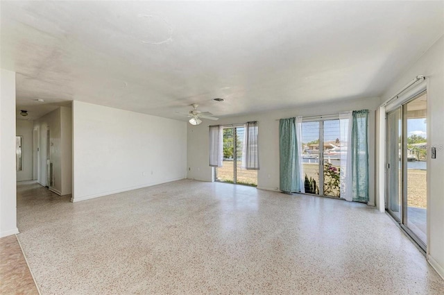 spare room with baseboards, speckled floor, and a ceiling fan