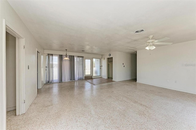 unfurnished room featuring visible vents, a ceiling fan, speckled floor, and baseboards