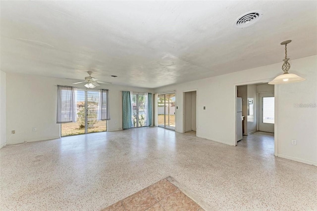 unfurnished living room with visible vents, light speckled floor, baseboards, and a ceiling fan