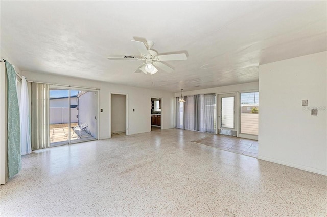 unfurnished room with a ceiling fan, speckled floor, and baseboards