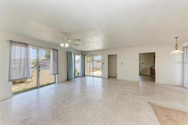 unfurnished room with baseboards, light speckled floor, and a ceiling fan