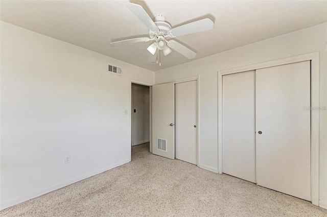 unfurnished bedroom with speckled floor, visible vents, two closets, and ceiling fan