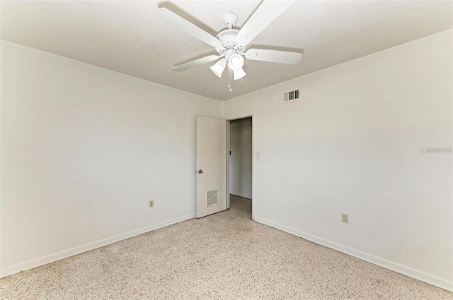 empty room featuring visible vents, baseboards, speckled floor, and a ceiling fan