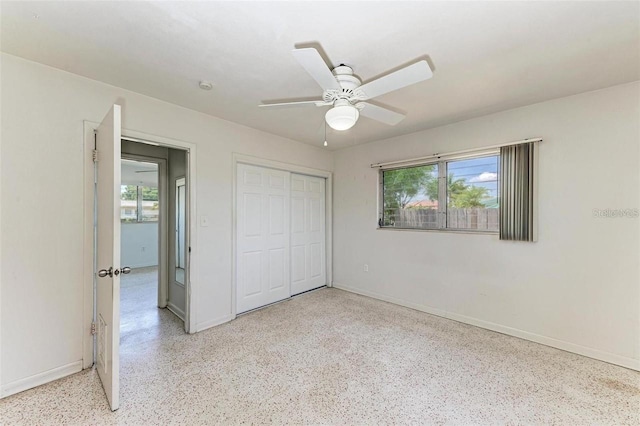 unfurnished bedroom featuring multiple windows, light speckled floor, baseboards, and a closet