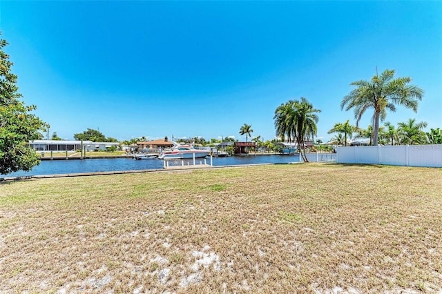 view of yard featuring fence, a water view, and a boat dock