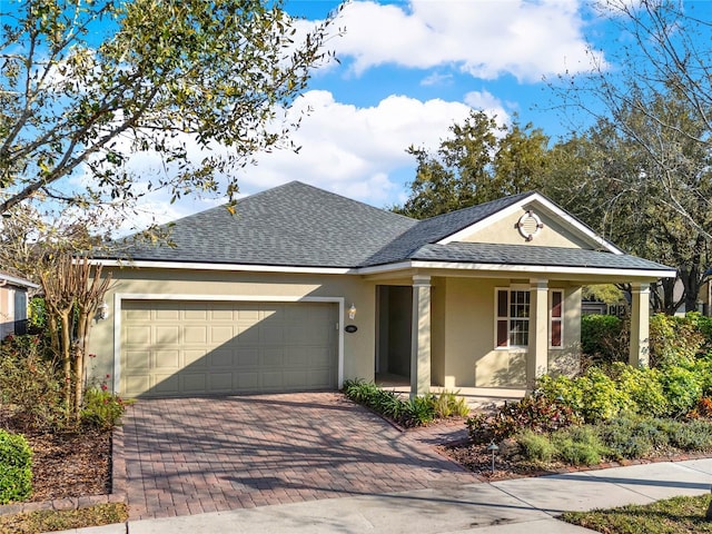 ranch-style house with stucco siding, an attached garage, decorative driveway, and roof with shingles