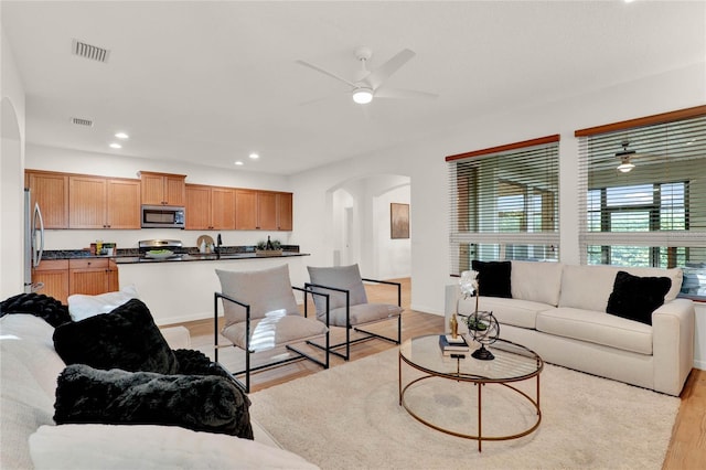 living room with arched walkways, visible vents, recessed lighting, and light wood-type flooring