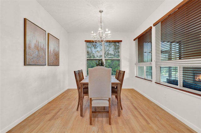 dining room featuring an inviting chandelier, baseboards, and light wood finished floors