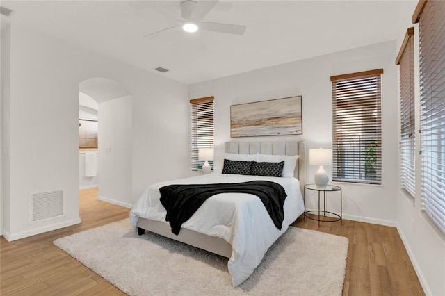 bedroom with visible vents, arched walkways, baseboards, and wood finished floors