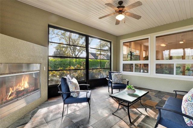 sunroom with a glass covered fireplace, wood ceiling, and ceiling fan