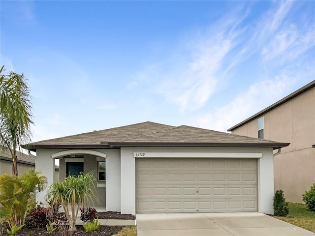 view of front facade with a garage, a shingled roof, concrete driveway, and stucco siding