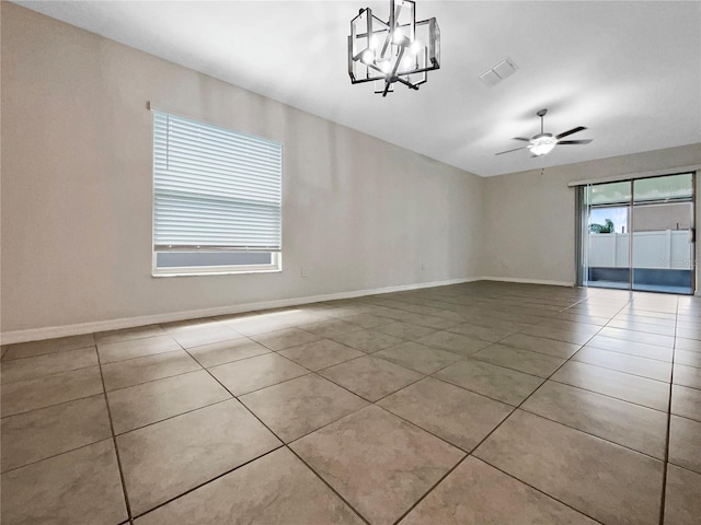 tiled empty room featuring visible vents, baseboards, and ceiling fan with notable chandelier