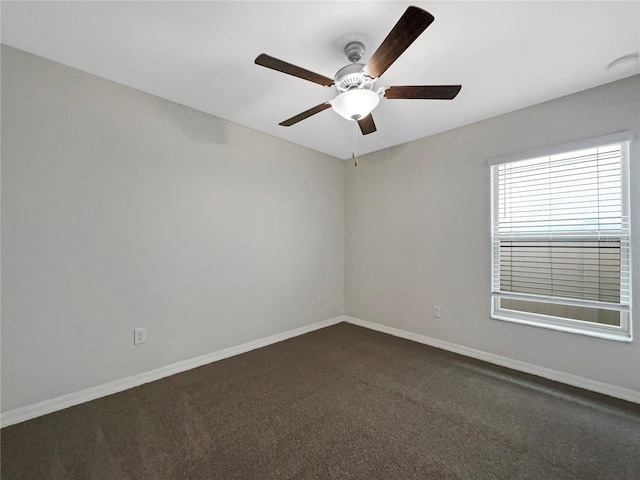 empty room featuring a ceiling fan, baseboards, and dark colored carpet