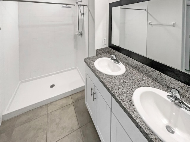 bathroom featuring tile patterned flooring, double vanity, a stall shower, and a sink