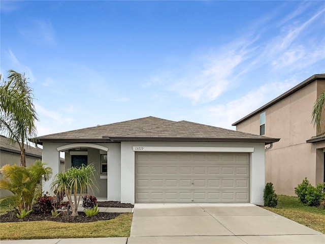 view of front of home featuring stucco siding, driveway, a shingled roof, and a garage