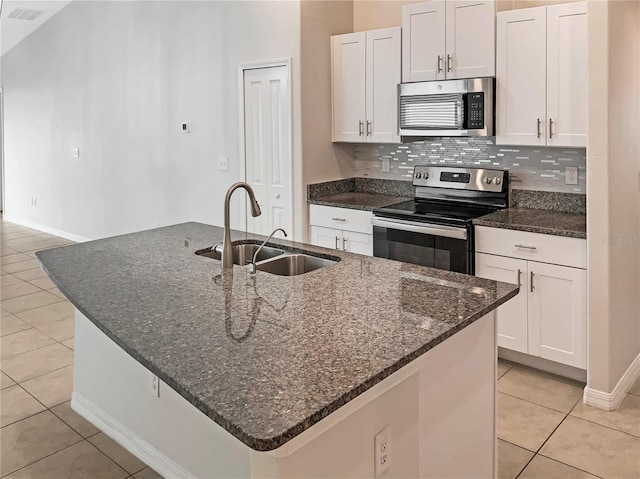 kitchen with visible vents, a center island with sink, a sink, decorative backsplash, and appliances with stainless steel finishes