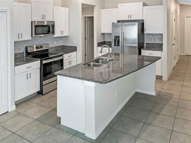 kitchen with a kitchen island with sink, a sink, white cabinetry, appliances with stainless steel finishes, and light tile patterned floors