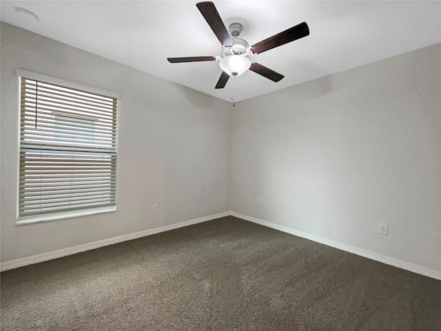 spare room with a ceiling fan, baseboards, and dark colored carpet