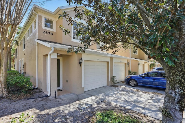 view of front of house with stucco siding, a garage, and driveway