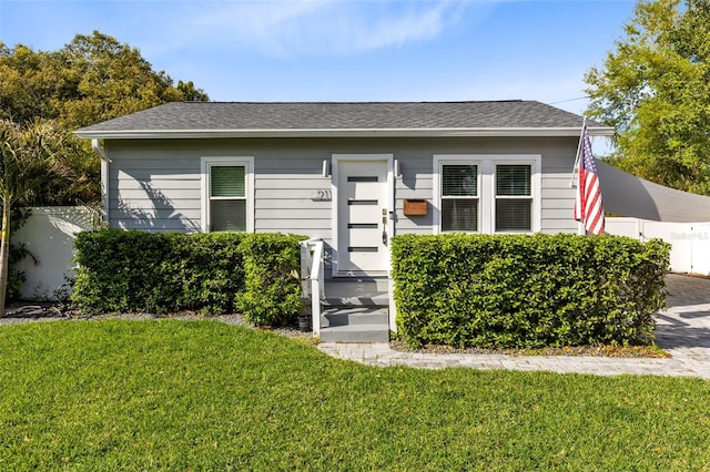 bungalow-style house featuring a shingled roof, a front yard, and fence