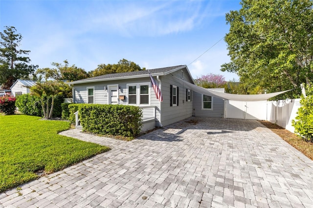 view of front of house featuring decorative driveway, a front lawn, and fence