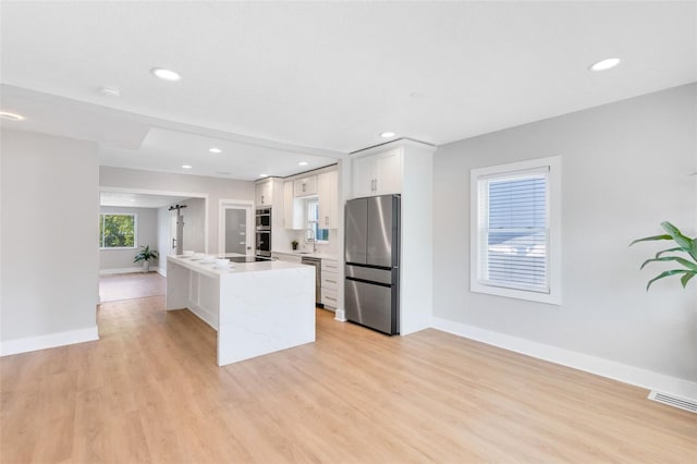 kitchen with stainless steel appliances, visible vents, light wood-style flooring, and light countertops