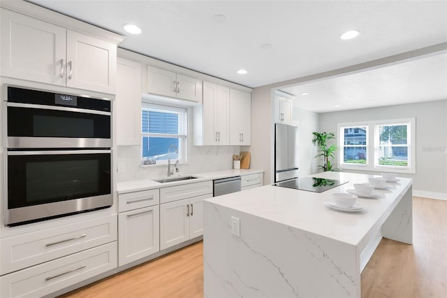 kitchen featuring plenty of natural light, a kitchen island, appliances with stainless steel finishes, and a sink