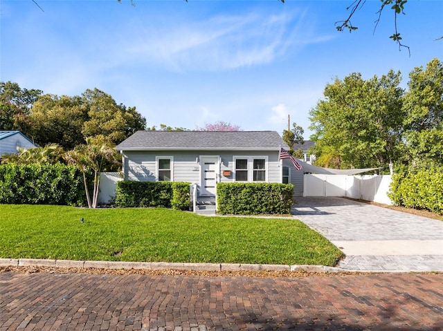 view of front of property featuring a front yard, decorative driveway, and fence