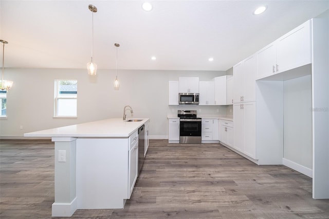 kitchen featuring light countertops, recessed lighting, wood finished floors, stainless steel appliances, and a sink