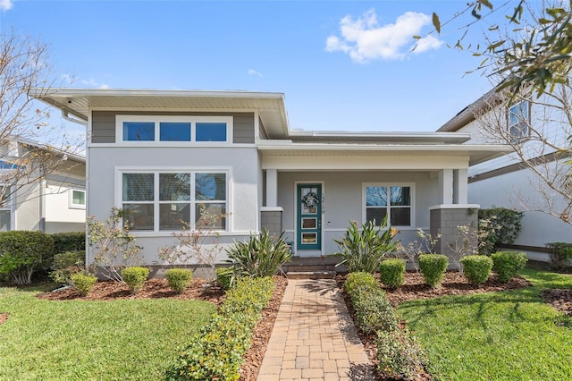 prairie-style home featuring stucco siding, covered porch, and a front yard