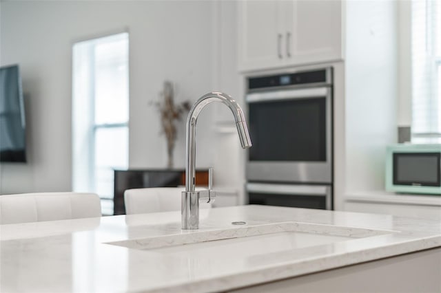 details featuring white microwave, double oven, and a sink